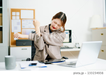 Overworked young Asian businesswoman office worker suffering from neck pain after had a long day at her office desk. 133154938
