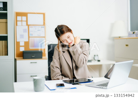 Overworked young Asian businesswoman office worker suffering from neck pain after had a long day at her office desk. Overworked young Asian businesswoman office worker suffering from neck pain after had a long day at her office desk. 133154942