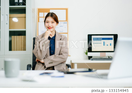 Young Asian businesswoman smiling and working with tablet and laptop in office. Concept of tax, report, accounting 133154945