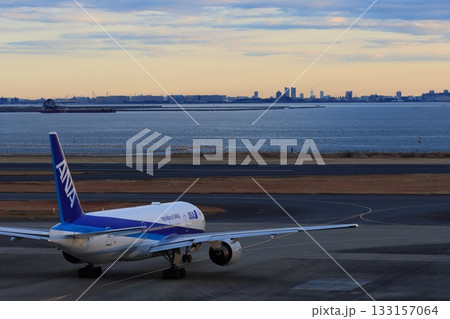 朝焼けの空に出発する旅客機　羽田空港の早朝便 133157064