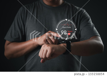 Man using smartwatch with heart rate monitor interface, representing wearable health technology and real-time fitness tracking. digital wellness solutions mobile health app. Man using smartwatch with heart rate monitor interface, representing wearable health technology and real-time fitness tracking. digital wellness solutions mobile health app. 133158854