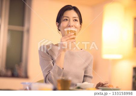 ビールを飲みながら夕食を食べるミドル女性 133158998