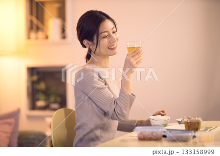 ビールを飲みながら夕食を食べるミドル女性 133158999