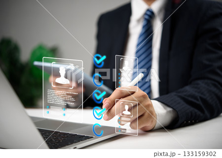 Businessman using digital interface to select candidates with virtual profile icons and checkmarks, representing modern recruitment, HR human resources technology, and hiring process. Businessman using digital interface to select candidates with virtual profile icons and checkmarks, representing modern recruitment, HR human resources technology, and hiring process. 133159302
