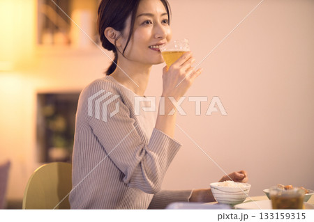 ビールを飲みながら夕食を食べるミドル女性 133159315