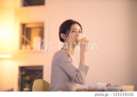 ビールを飲みながら夕食を食べるミドル女性 133159316