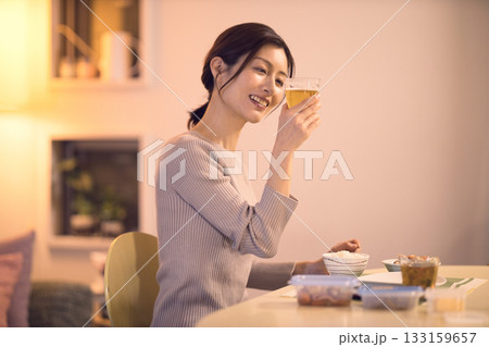 ビールを飲みながら夕食を食べるミドル女性 133159657