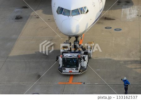 トーイングトラクターに牽引されスポットに入る旅客機 出発準備 トーイングトラクターに牽引されスポットに入る旅客機 出発準備 133162537