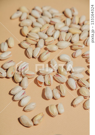 Salted pistachios in their shells are scattered on a soft beige background Salted pistachios in their shells are scattered on a soft beige background 133164324
