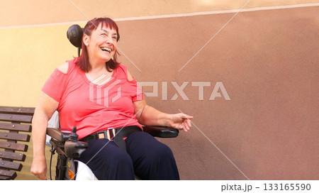 Smiling woman with physical disability in electric wheelchair Smiling woman with physical disability in electric wheelchair 133165590