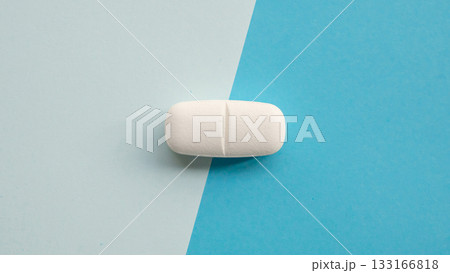 White medicine pill tablet on blue and white background 133166818