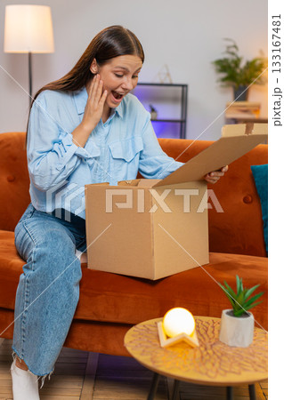 Happy woman girl shopper unpacking cardboard box delivery parcel online shopping purchase at home 133167481