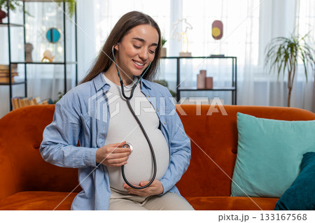 Happy pregnant young woman using stethoscope listening to baby heartbeat unborn child vital signs Happy pregnant young woman using stethoscope listening to baby heartbeat unborn child vital signs 133167568
