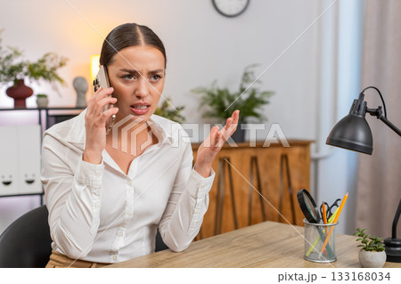 Young businesswoman argues on smartphone waves palm no no shows irritation and raises voice on call Young businesswoman argues on smartphone waves palm no no shows irritation and raises voice on call 133168034