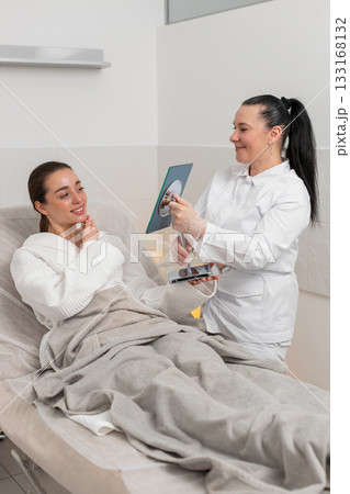 Caucasian young woman smiling in mirror after cosmetic procedure in clinic with visible skin results Caucasian young woman smiling in mirror after cosmetic procedure in clinic with visible skin results 133168132