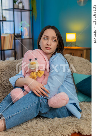 Woman on sofa hugging plush bunny feeling lonely romantic missing beloved tenderness, divorce Woman on sofa hugging plush bunny feeling lonely romantic missing beloved tenderness, divorce 133168135
