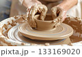 Muddy hands shaping clay on a potters wheel 133169020