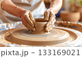 Potter shapes wet clay on wheel 133169021