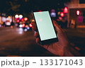 Person is holding a cell phone in a dark city street 133171043