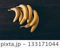 Bunch of bananas are sitting on a wooden table 133171044
