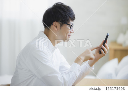 ベッドルームでスマホを見る男性 ベッドルームでスマホを見る男性 133173698
