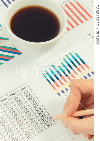 Cup of coffee and finger showing financial chart with production or sales statistics. Business Cup of coffee and finger showing financial chart with production or sales statistics. Business 133173971