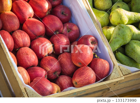Apples and pears in wooden box on stand at bazaar. Healthy fruits as source minerals and vitamins Apples and pears in wooden box on stand at bazaar. Healthy fruits as source minerals and vitamins 133173990