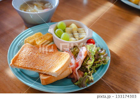 トーストや玉子焼き、ベーコンとフルーツを盛り付けた彩り豊かな朝食プレート 133174303