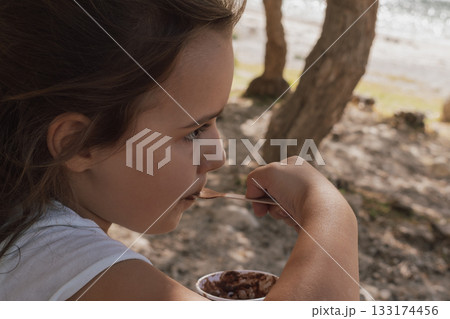 Simple summer joy: child enjoying a scoop of ice cream on a sunny day Simple summer joy: child enjoying a scoop of ice cream on a sunny day 133174456