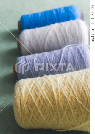 Variety colours of alpaca wool and silk. Cones of multicoloured yarn. Wool threads in a row. Row of blue, white, yellow and grey wool. Knitting hobby. Bobbins of yarn. Bright wool for knitting. Variety colours of alpaca wool and silk. Cones of multicoloured yarn. Wool threads in a row. Row of blue, white, yellow and grey wool. Knitting hobby. Bobbins of yarn. Bright wool for knitting. 133175175