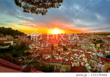 Beautiful sunset over Lisbon, Portugal, cloudy sky, sun setting behind April 25th or 25 de Abril bridge, over rooftops, Tagus or Tejo river, Sao Jorge castle hill. Travel destination, tourist Beautiful sunset over Lisbon, Portugal, cloudy sky, sun setting behind April 25th or 25 de Abril bridge, over rooftops, Tagus or Tejo river, Sao Jorge castle hill. Travel destination, tourist 133176468