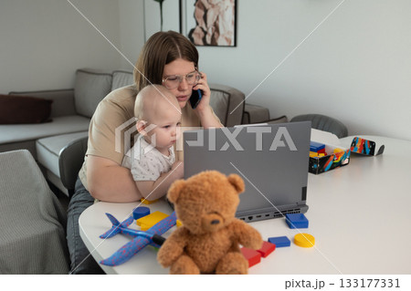 adult manages work and child, parent juggles professional duties and entertaining young children 133177331