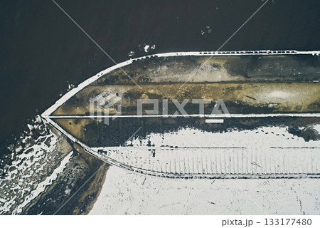 Aerial view of an abandoned wooden ship at the bottom of the river in winter against the backdrop of white snow and black water close-up 133177480