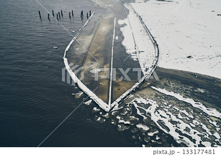 Aerial view of an abandoned wooden ship at the bottom of the river in winter against the backdrop of white snow and black water Aerial view of an abandoned wooden ship at the bottom of the river in winter against the backdrop of white snow and black water 133177481