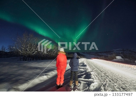 Aurora Borealis on a journey, a couple of girls on the road look at the night sky Aurora Borealis on a journey, a couple of girls on the road look at the night sky 133177497