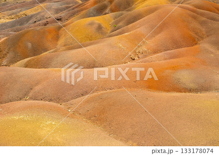 Close view of Chamarel Seven Coloured Earth rippled dunes with warm tones, soft curves, and fine granular texture Close view of Chamarel Seven Coloured Earth rippled dunes with warm tones, soft curves, and fine granular texture 133178074
