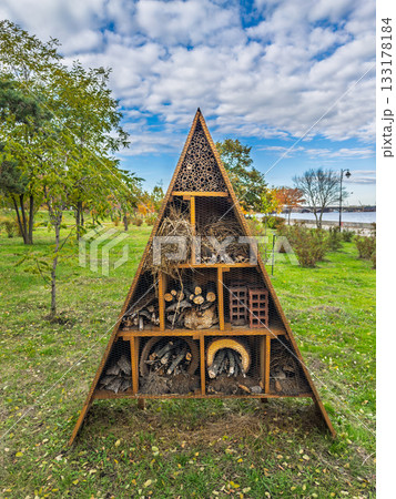 Large triangular insect hotel structure in urban park near lake with natural materials for biodiversity Large triangular insect hotel structure in urban park near lake with natural materials for biodiversity 133178184