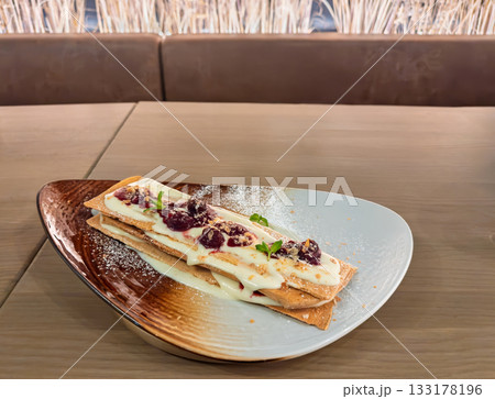 Gourmet mille feuille pastry with vanilla cream and berry compote served on ceramic plate restaurant Gourmet mille feuille pastry with vanilla cream and berry compote served on ceramic plate restaurant 133178196