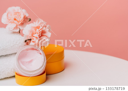Open cream jar with carnations on towel Open cream jar with carnations on towel 133178719