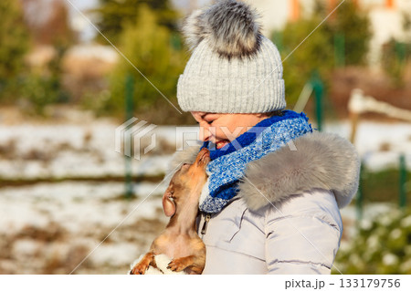 Woman playing with dog during winter Woman playing with dog during winter 133179756