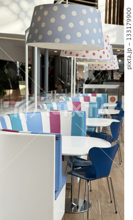 Empty modern cafe interior with colorful seating and polka dot lampshades in natural light Empty modern cafe interior with colorful seating and polka dot lampshades in natural light 133179900