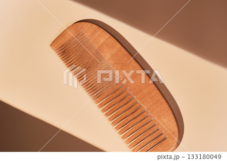 Wooden comb on beige background receiving sunlight 133180049