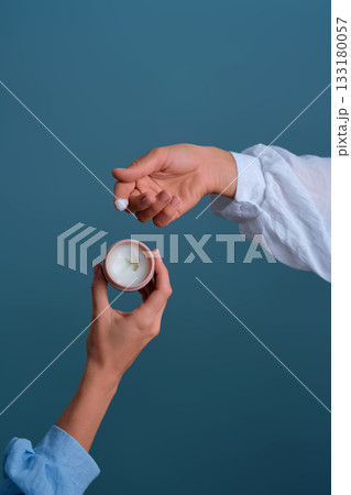 Hands sharing skincare cream pot for beauty routine 133180057