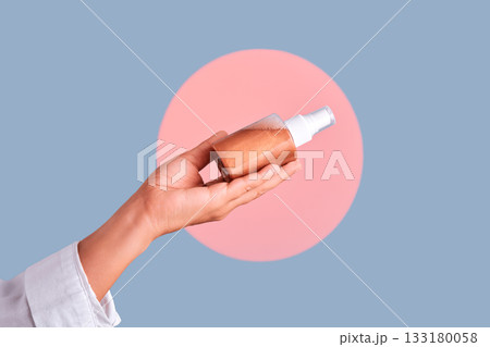 Hand holding self-tan spray bottle for skincare Hand holding self-tan spray bottle for skincare 133180058