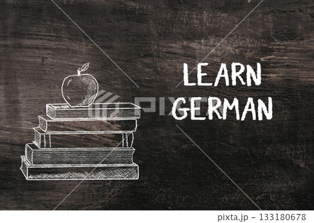 Stack of books with apple on top and text promoting learning German language skills Stack of books with apple on top and text promoting learning German language skills 133180678