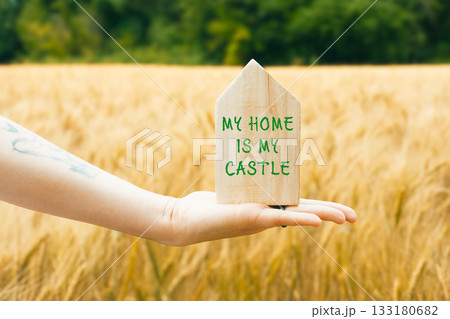 Hand holding wooden house sign with inspirational quote in golden wheat field landscape Hand holding wooden house sign with inspirational quote in golden wheat field landscape 133180682