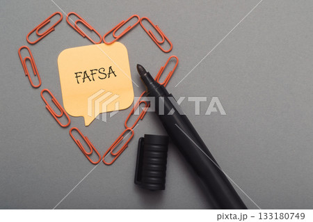 A pen with a piece of paper with the word FAFSA written on it A pen with a piece of paper with the word FAFSA written on it 133180749