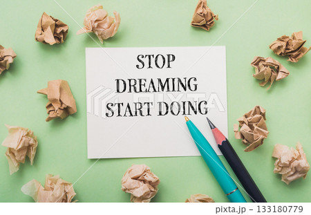 Piece of paper with the words Stop dreaming start doing written on it 133180779
