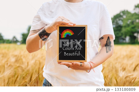 Woman holds a rainbow and a sign that says Your true colors are beautiful. Woman holds a rainbow and a sign that says Your true colors are beautiful. 133180809