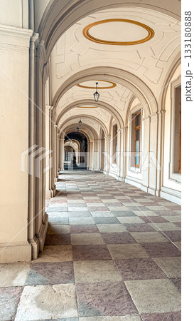Elegant architectural corridor with arched ceilings and patterned stone flooring, showcasing a serene passageway filled with natural light and historical charm 133180888